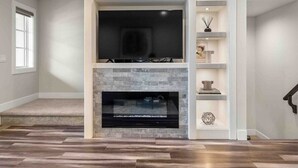 Uma sala de estar moderna com lareira, TV integrada e estante.