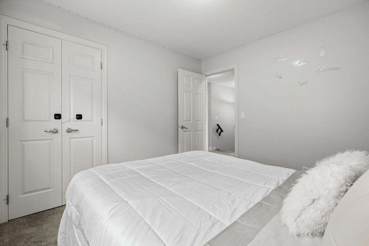A bedroom with a large bed, two white doors, and a wall with decorative elements.