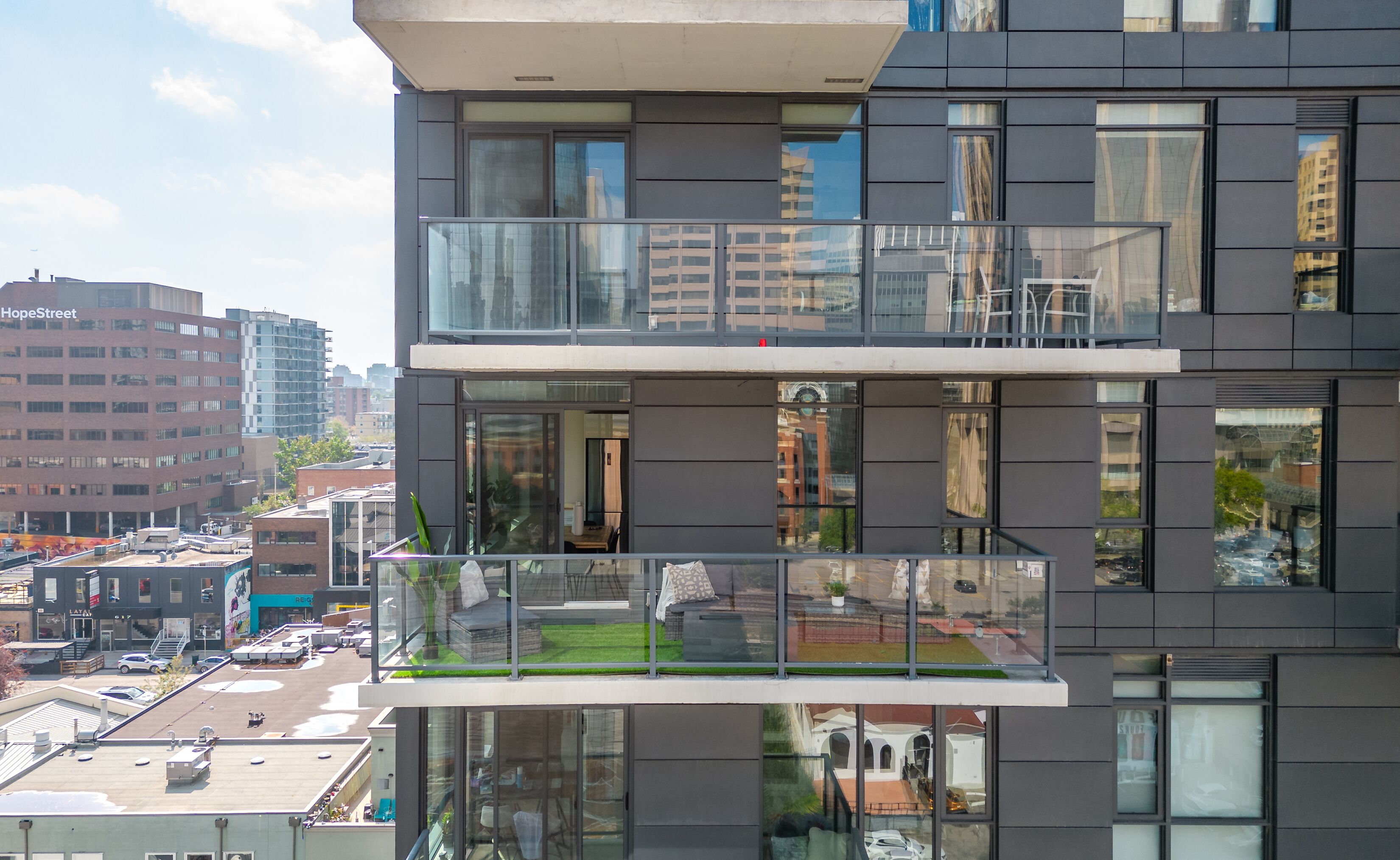 A modern building with a glass balcony, large windows, and a view of the cityscape.