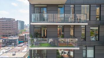 A modern building with a glass balcony, large windows, and a view of the cityscape.