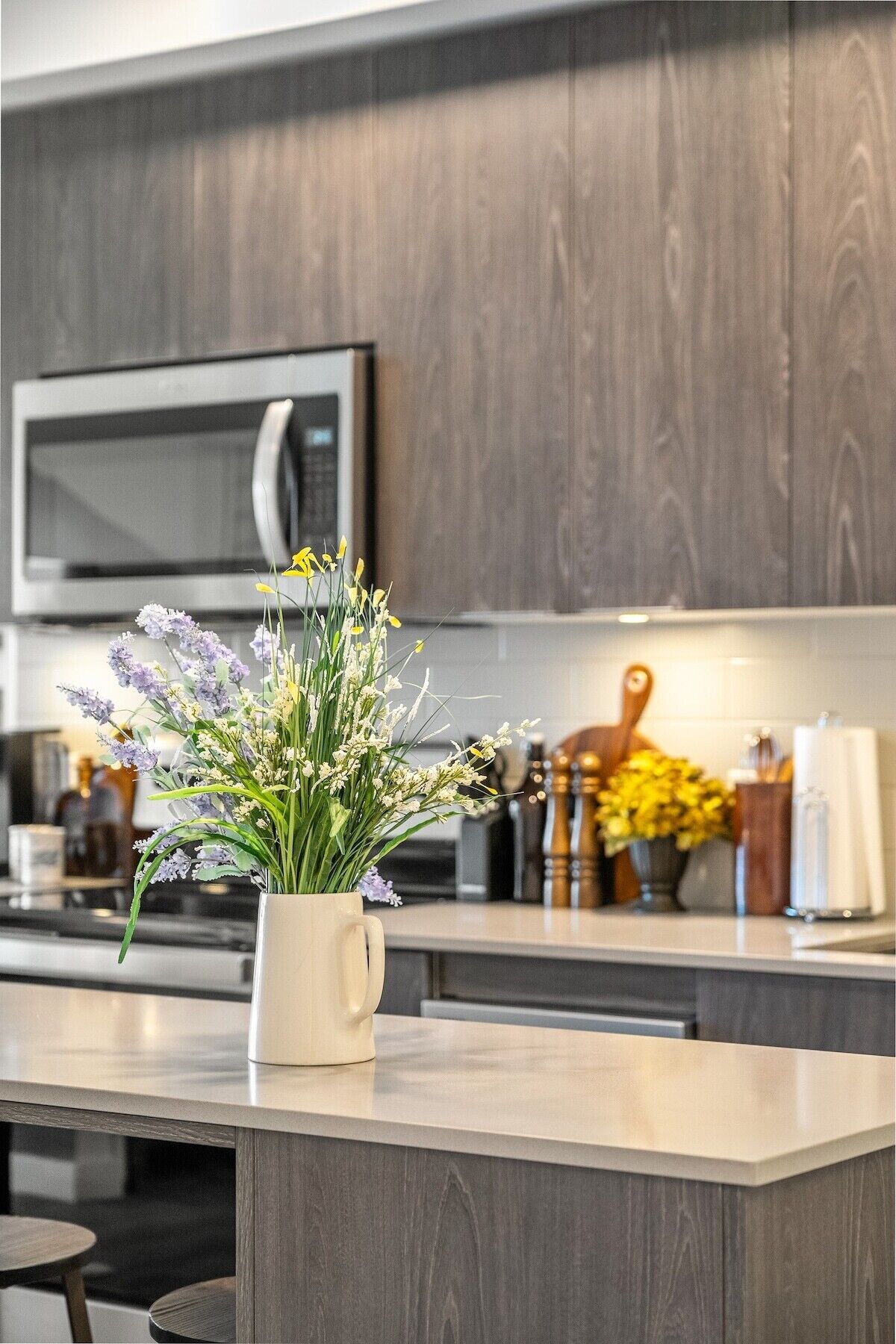 A modern kitchen with dark wood cabinets, a microwave, and a white countertop.