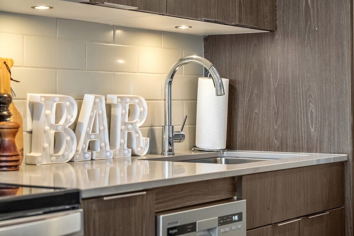 A modern kitchen with a stainless steel sink, a dishwasher, and wooden cabinets.