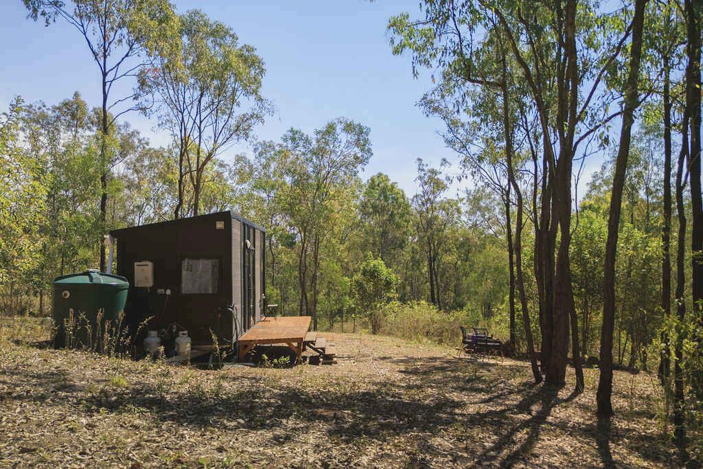 A rustic cabin with a small porch, surrounded by a forest.