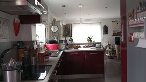 Une cuisine moderne dotée d’un îlot central, d’appareils électroménagers en acier inoxydable et d’un meuble rouge.
