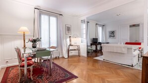 A spacious living room with a dining area, wooden flooring, and a white sofa. - Mindful Enlightenment, by Veeve (Paris)