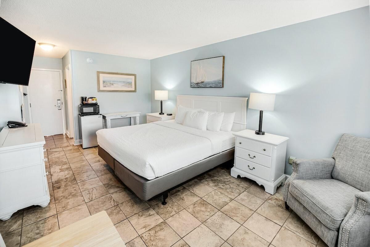Une chambre d’hôtel avec un lit, des tables de chevet, une télévision et une chaise.