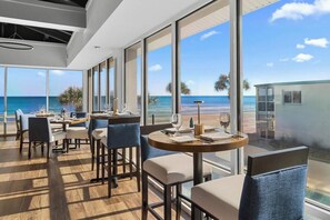 A modern dining area with large windows, wooden flooring, and a view of the ocean. - Ultimate Getaway Resort View King Room 1st Flr (Pawleys Island)
