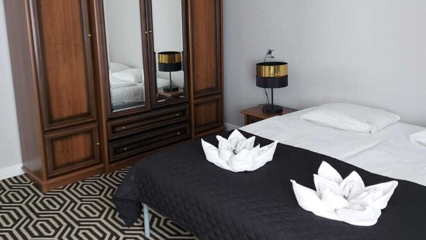 A hotel room with a large wardrobe, a bed with a black and white patterned bedspread, and a modern lamp. - Apartament Konopnicka (Swinoujscie)
