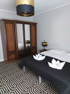 Una camera d'albergo con un ampio armadio, un letto con copriletto a motivi bianco e neri e una lampada moderna.