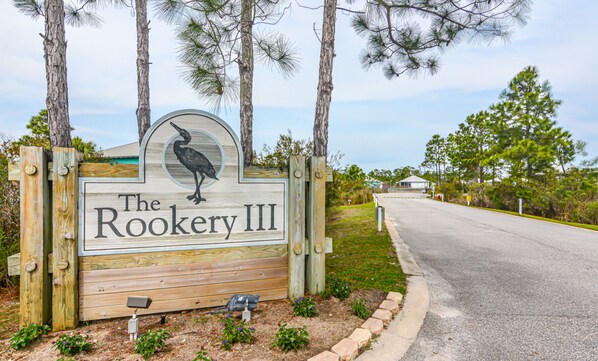 A wooden sign with a bird logo and the text "The Rookery III" for a property.