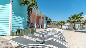 A row of sun loungers aligned on a paved area with a pool in the background. - 6015 Rookery 3 Tropic like is hot (Gulf Shores)
