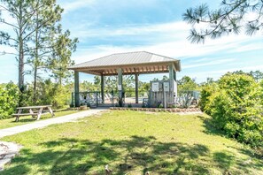 Un kiosque doté d’un toit en métal, entouré d’une pelouse et d’arbres.