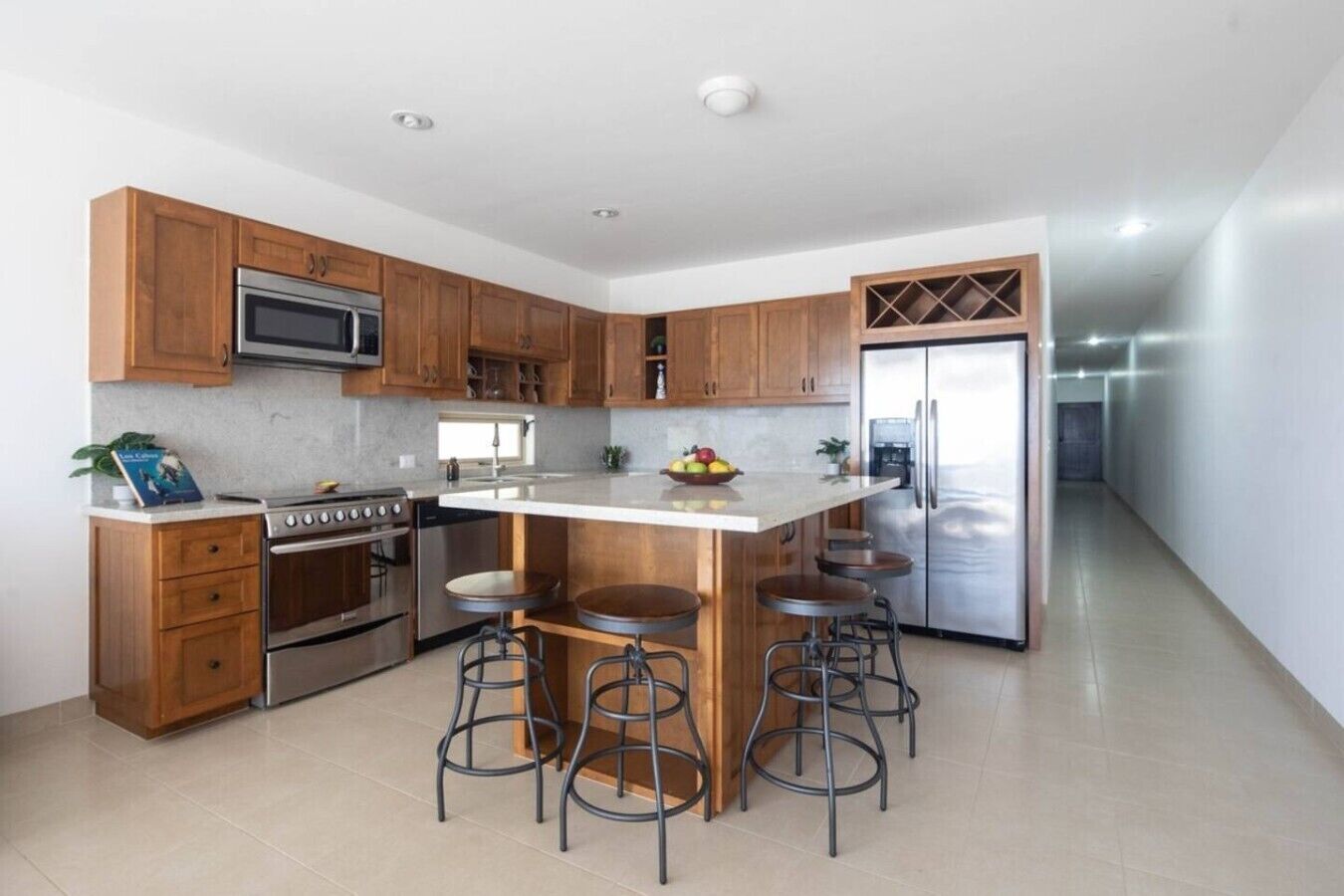 A modern kitchen with wooden cabinets, stainless steel appliances, and a central island with bar stools.