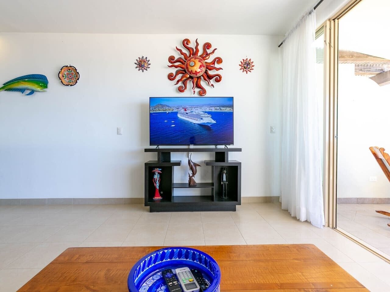 Een woonkamer met een flatscreen televisie, decoratieve muurkunst en een houten salontafel.