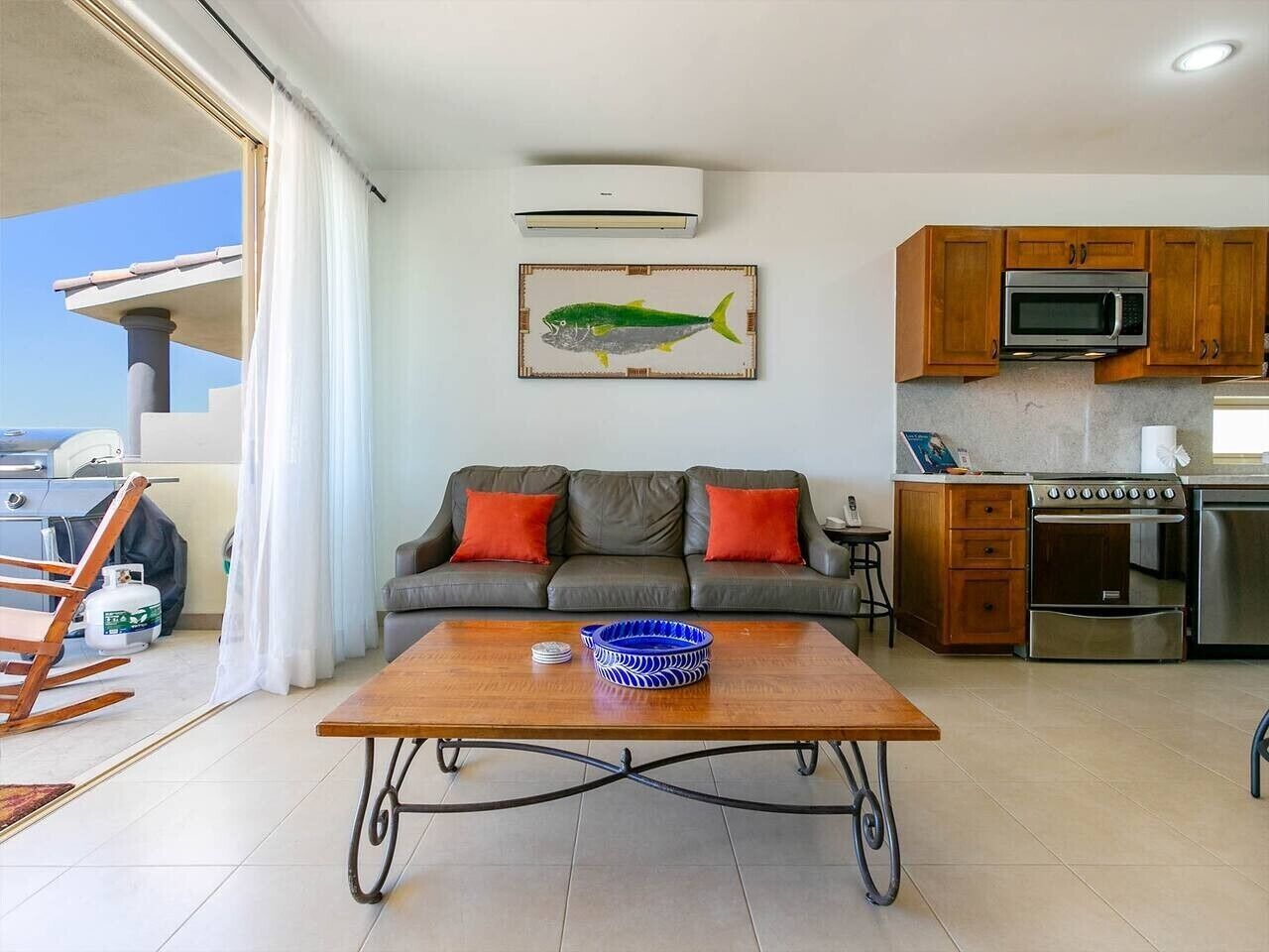 Ein Wohnzimmer mit einer Couch, einem Couchtisch und einer Küchenzeile mit Mikrowelle und Backofen.