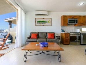 Un soggiorno con divano, tavolino e angolo cottura con forno a microonde e forno.