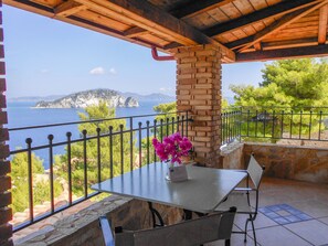 Enjoy breathtaking sea views from this outdoor space, featuring a table, chairs, and beautiful flower arrangement.