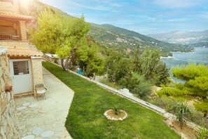 Stroll along the manicured lawn to the stone entrance, surrounded by lush trees and a serene landscape.