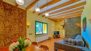 Un comedor con una mesa y sillas de madera, una pared de piedra, una chimenea de piedra y un televisor al fondo.