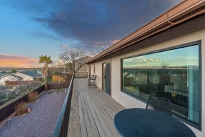 Une maison moderne dotée d’une terrasse en bois, de grandes fenêtres et offrant une vue sur le paysage environnant.
