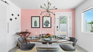 A dining area with a round table, four chairs, a chandelier, and framed cactus artwork on the wall. - Beautiful home in the highly desirable Tahquitz Estates neighborhood. (Palm Springs)