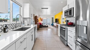A modern kitchen with white cabinets, stainless steel appliances, and a large window. - Beautiful home in the highly desirable Tahquitz Estates neighborhood. (Palm Springs)