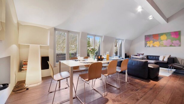 Een moderne loft met een eethoek, zitplaatsen en een groot raam.