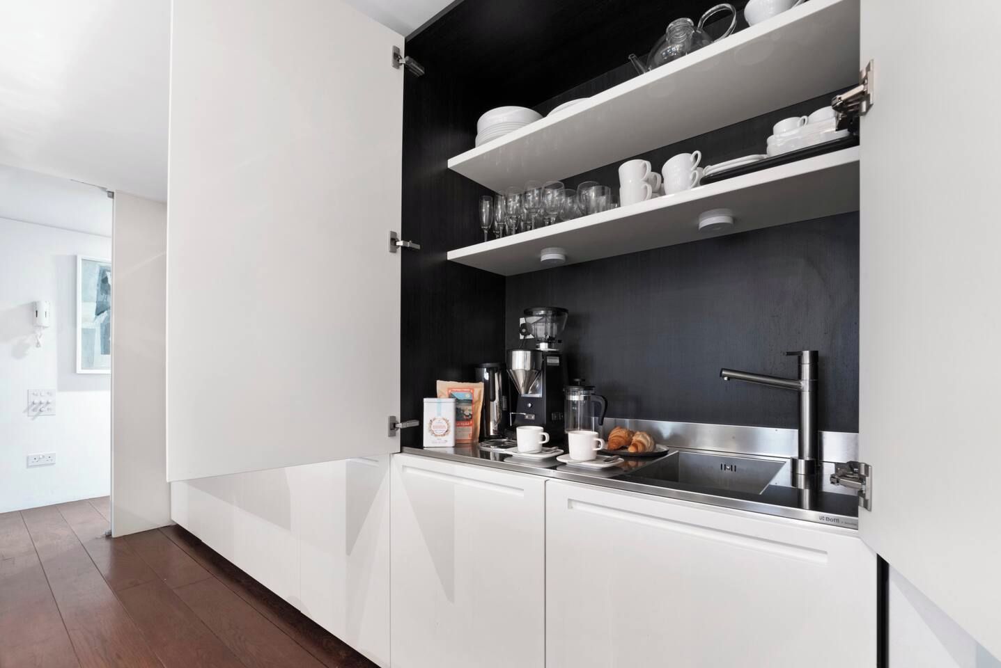 Une cuisine moderne avec des meubles blancs, un plan de travail noir et un évier en acier inoxydable.