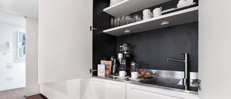 Une cuisine moderne avec des meubles blancs, un plan de travail noir et un évier en acier inoxydable.