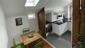 A compact kitchen with white cabinets, a black countertop, and a skylight above the dining area. - Cozy Apartment, Refurbished but Keeping the Ancient Style of old Lisbon (Lisboa)