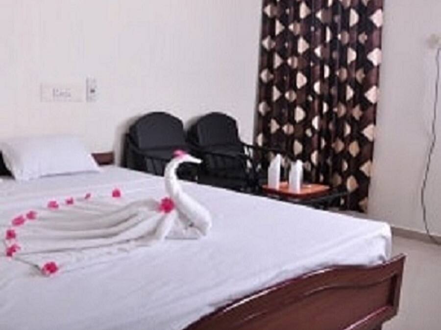 Habitación de hotel con una cama, una silla, un escritorio y una cortina de estampado geométrico.