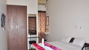Une chambre d’hôtel avec un lit en bois, une chaise, un bureau et un téléviseur fixé au mur.