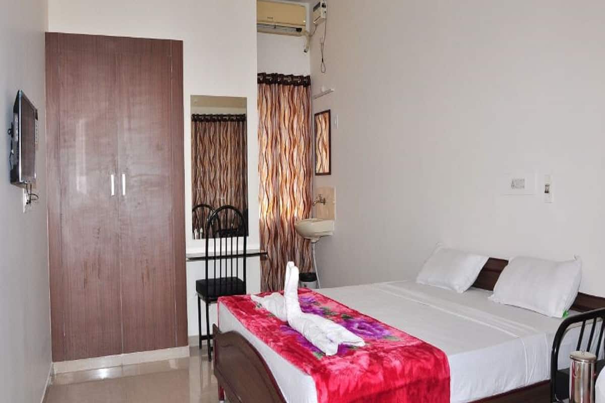 Habitación de hotel con cama de madera, una silla, un escritorio y televisor montado en la pared.