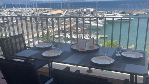 A balcony table set with plates, glasses, and candles, overlooking a marina with boats and a clear view of the sea. - Air-conditioned apartment with terraces and port view, near beaches in Hyères (Hyères)