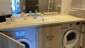 A modern laundry room with a built-in washing machine and dryer, a sink, and a mirror above the counter. - Air-conditioned apartment with terraces and port view, near beaches in Hyères (Hyères)