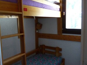 Cozy retreat with a bunk bed, window, and storage shelf.