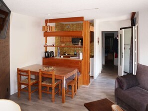 Una cocina compacta con armarios de madera, una mesa de comedor con sillas y un sofá en la sala.