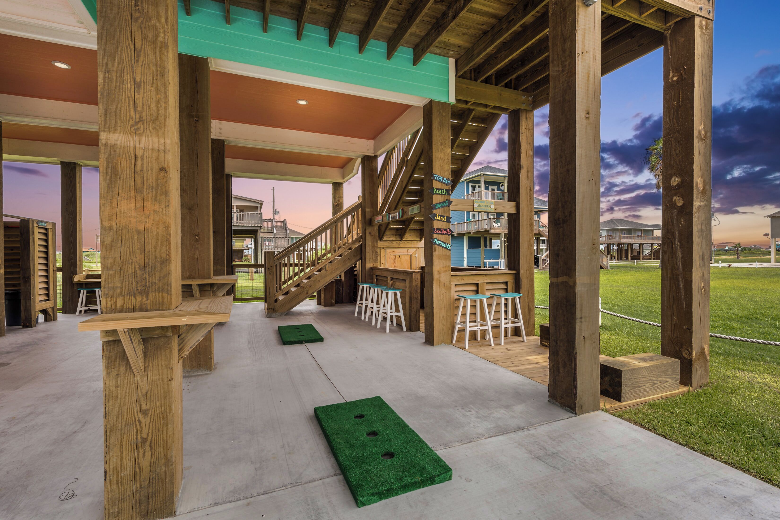 Un espacio al aire libre cubierto con vigas de madera, una escalera y vistas a casas al fondo.