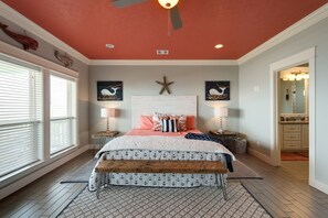 A bedroom with a bed, a ceiling fan, a nightstand, a bench, and a window with blinds.