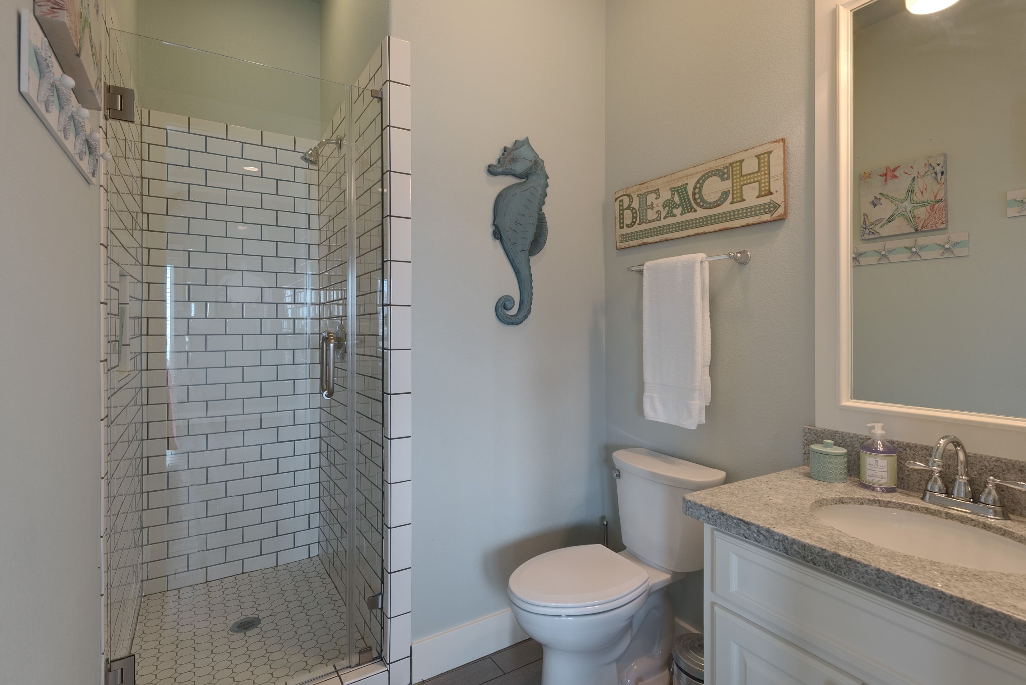 A bathroom with a glass-enclosed shower, a toilet, and a vanity with a sink.