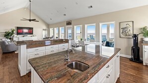 Una cocina amplia con una isla grande, armarios blancos y vistas a la ciudad.