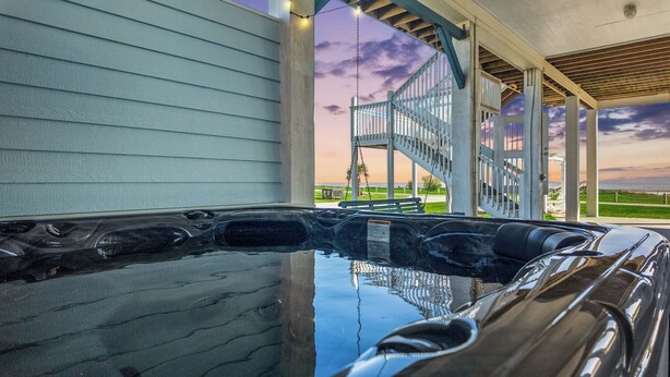 Un jacuzzi con vistas a un área exterior techada y una escalera que lleva a una terraza.
