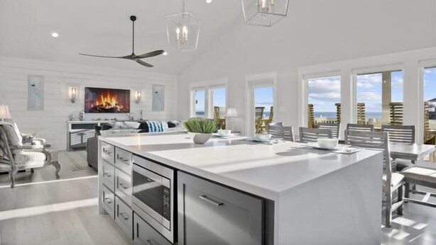A spacious kitchen with a large island, modern appliances, and a dining area with a view. - Gulf Views | Modern Amenities, Deck, Sleeps 12 & More (Port Bolivar)