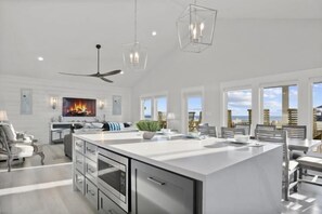 A spacious kitchen with a large island, modern appliances, and a dining area with a view. - Gulf Views | Modern Amenities, Deck, Sleeps 12 & More (Port Bolivar)