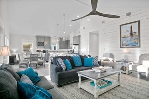 A modern living room with a dark sofa, a coffee table, and a dining area in the background.