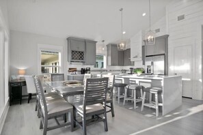 A modern kitchen with a central island, grey cabinets, and pendant lighting.
