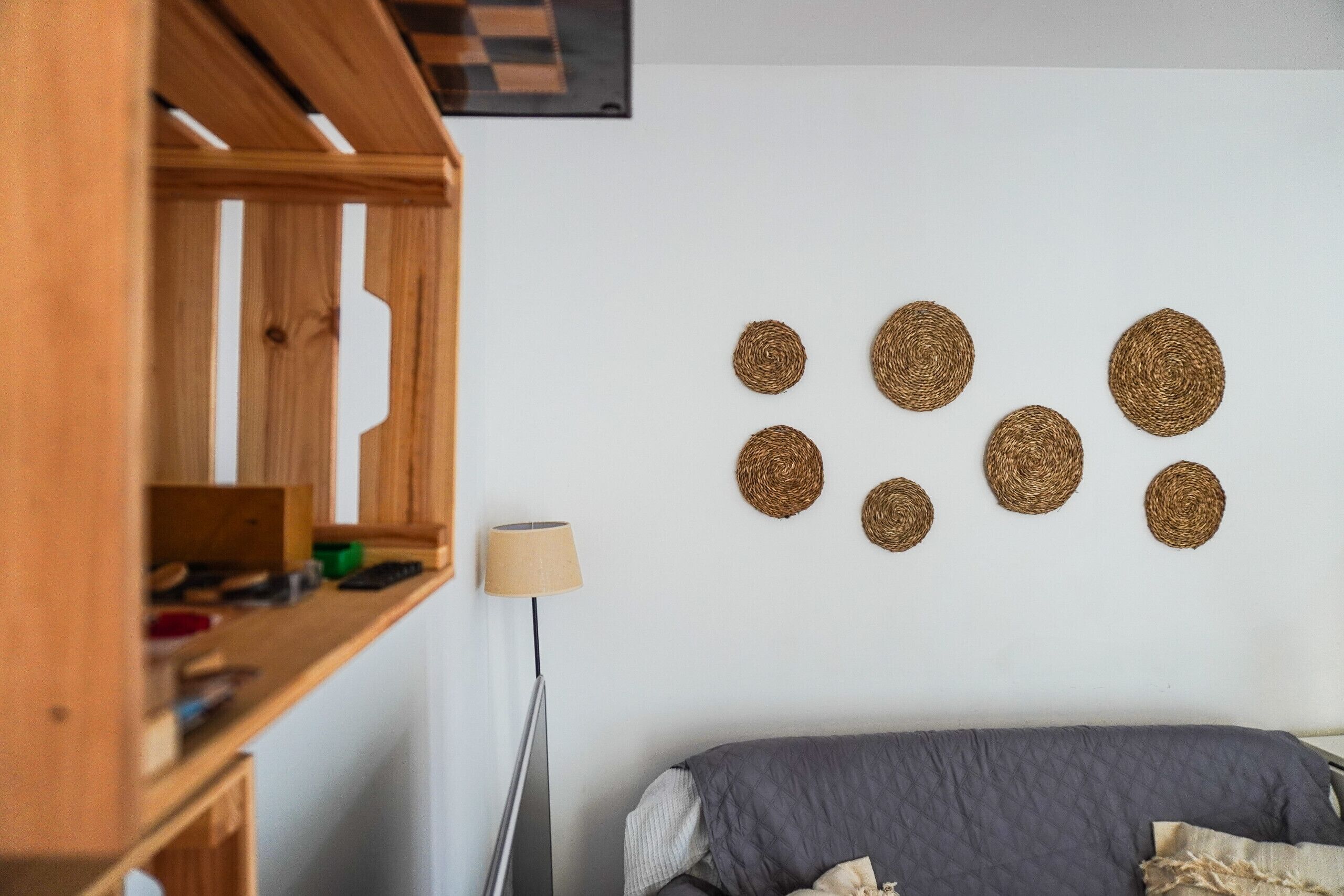 Une chambre à coucher avec un lit, une armoire en bois et des décorations murales en fibres tressées.