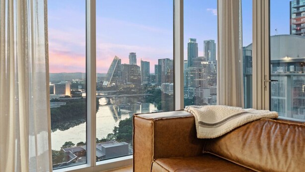 Een kamer met een groot raam met uitzicht op een stadsgezicht en een rivier.