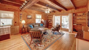 A cozy cabin interior with a wooden ceiling, a fireplace, a sofa, a coffee table, and a bookshelf. - Lucky Tern - Ocracoke Island (Ocracoke)