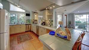 Una cocina amplia con armarios blancos, salpicadero de azulejos y un ventanal grande.